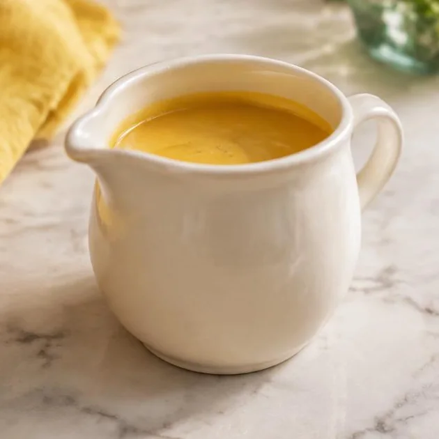 Glatte goldgelbe Sauce in einer kleinen Keramiksauciere